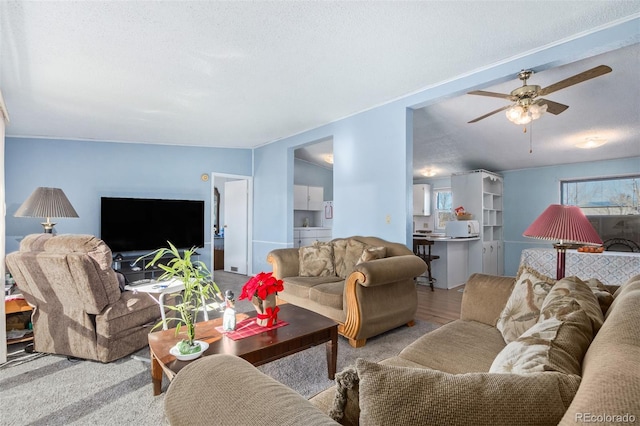 living room featuring ceiling fan, light hardwood / wood-style floors, and a textured ceiling