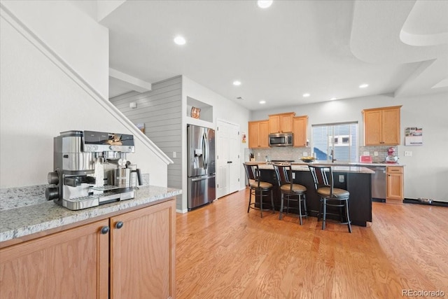 5100 Eaglewood Ln, Johnstown, CO 80534 - kitchen with stainless steel appliances, light brown cabinets, a kitchen breakfast bar, light wood-style flooring, and a kitchen island