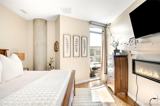 4200 W 17th Ave Unit 611, Denver, CO 80204 - bedroom featuring light wood finished floors, baseboards, and a glass covered fireplace