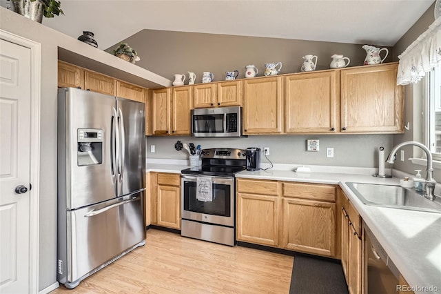 kitchen featuring a sink, light wood-style floors, appliances with stainless steel finishes, light countertops, and vaulted ceiling