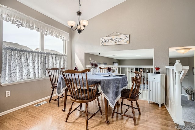 dining area with lofted ceiling, wood finished floors, visible vents, and baseboards