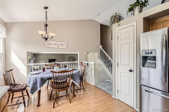 dining room with light wood finished floors and vaulted ceiling