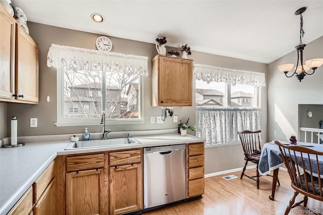 kitchen with dishwasher, light countertops, light wood-style floors, and a sink