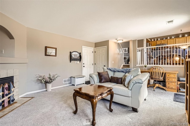 living area featuring baseboards, light colored carpet, visible vents, and a tile fireplace