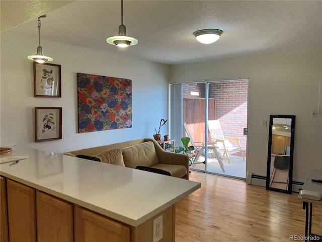 kitchen featuring light hardwood / wood-style flooring, a baseboard heating unit, a textured ceiling, decorative light fixtures, and kitchen peninsula