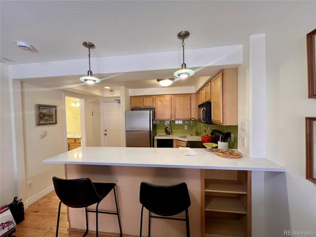 kitchen featuring light hardwood / wood-style flooring, pendant lighting, stainless steel fridge, sink, and kitchen peninsula