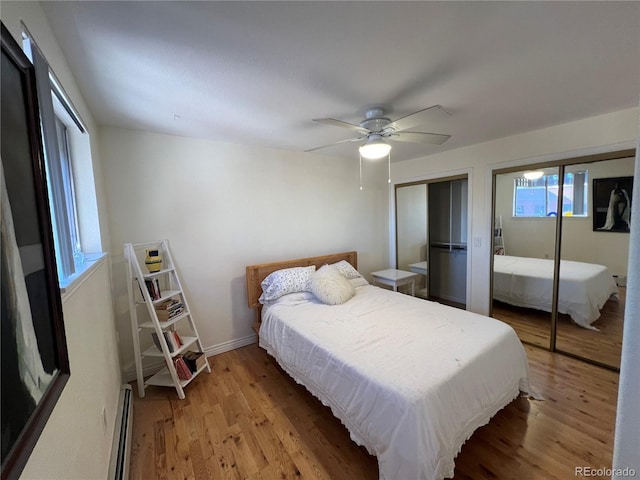 bedroom featuring light hardwood / wood-style floors, ceiling fan, a baseboard radiator, and two closets