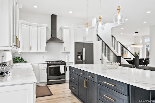 kitchen with wall chimney exhaust hood, appliances with stainless steel finishes, white cabinets, and decorative backsplash