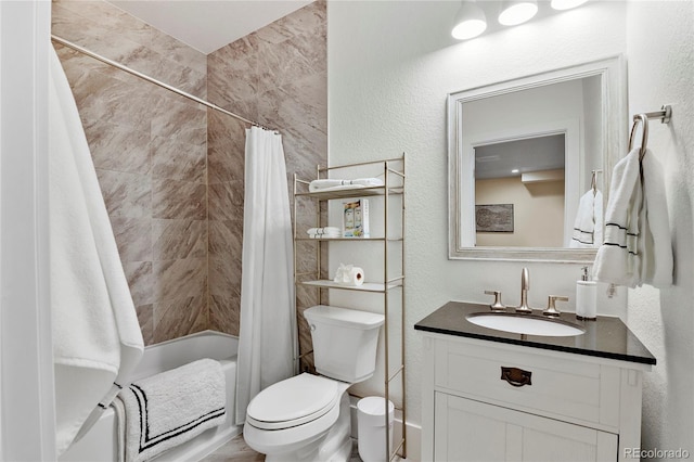 bathroom featuring toilet, a textured wall, shower / bathtub combination with curtain, and vanity