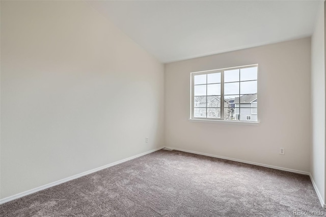 carpeted spare room featuring baseboards and vaulted ceiling