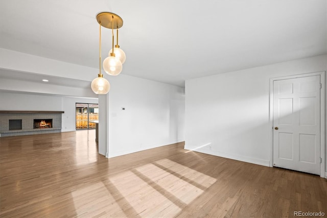 unfurnished room featuring hardwood / wood-style floors and a brick fireplace