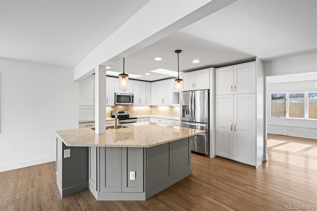 kitchen featuring light stone counters, white cabinets, hanging light fixtures, and appliances with stainless steel finishes