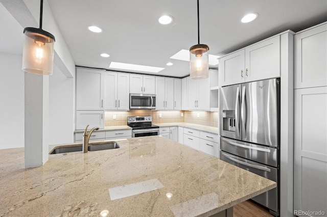 kitchen with pendant lighting, light stone countertops, white cabinetry, and appliances with stainless steel finishes