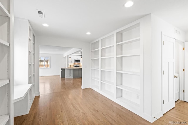 hallway with light hardwood / wood-style flooring and built in features