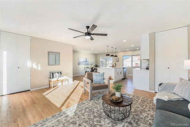 living room with sink, ceiling fan, and light hardwood / wood-style flooring