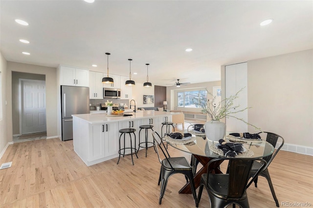 dining area with sink, light hardwood / wood-style floors, and ceiling fan