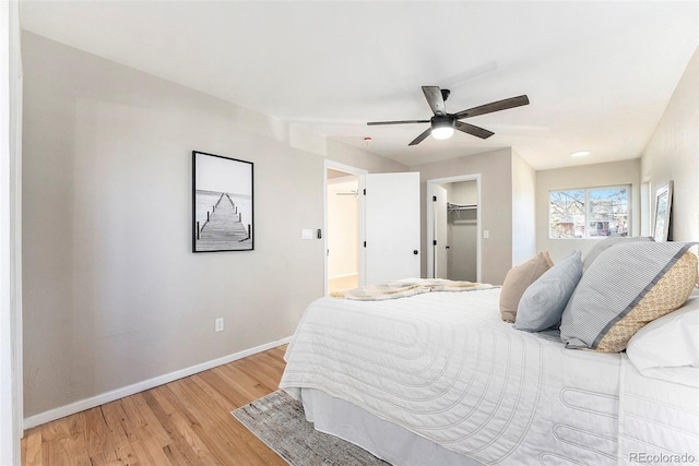 bedroom featuring ceiling fan, a spacious closet, and light hardwood / wood-style flooring