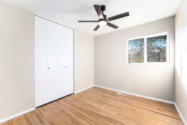 unfurnished bedroom with ceiling fan, light wood-type flooring, and a closet