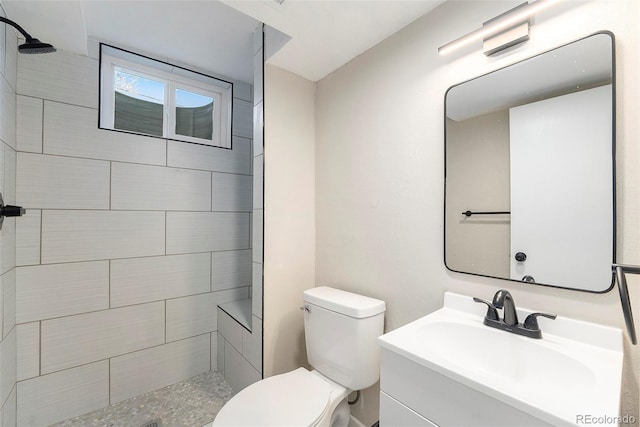 bathroom with vanity, tiled shower, and toilet