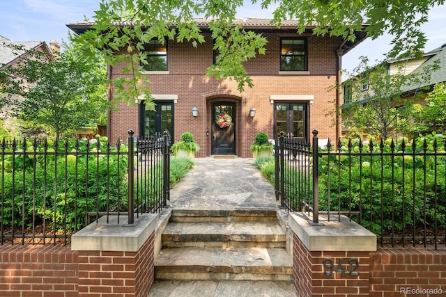 view of front of home featuring brick siding, a fenced front yard, and a gate