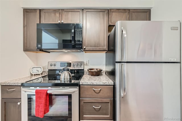 kitchen featuring appliances with stainless steel finishes and light stone counters