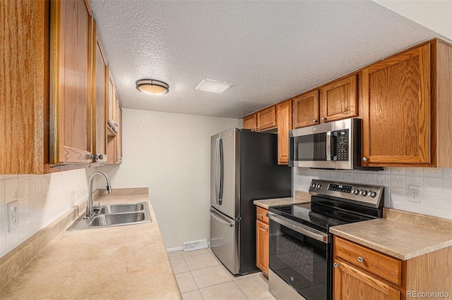 kitchen with backsplash, a textured ceiling, stainless steel appliances, sink, and light tile patterned floors