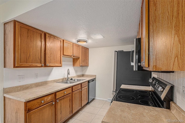 kitchen featuring sink, stainless steel appliances, backsplash, a textured ceiling, and light tile patterned floors