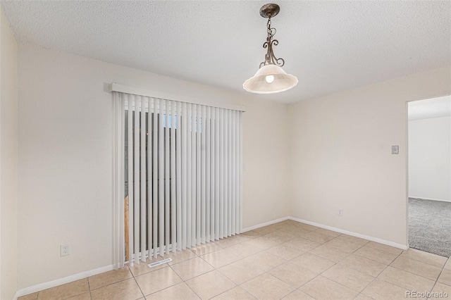 spare room with a textured ceiling and light tile patterned flooring