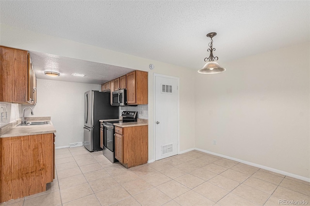 kitchen featuring pendant lighting, sink, a textured ceiling, tasteful backsplash, and stainless steel appliances