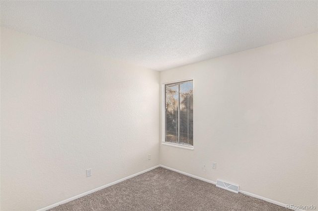 carpeted spare room featuring a textured ceiling