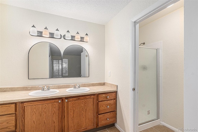 bathroom with tile patterned floors, vanity, a textured ceiling, and walk in shower