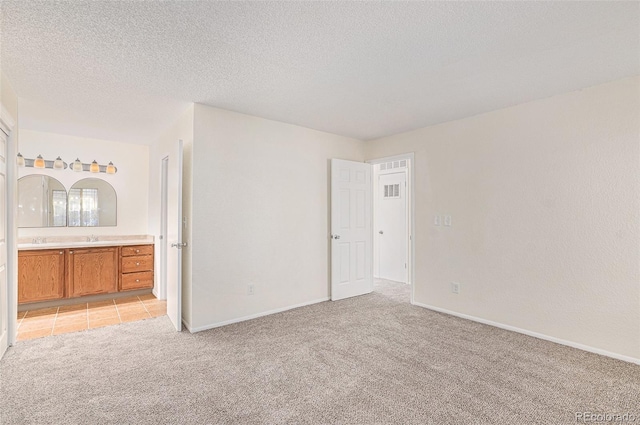 unfurnished room with light carpet, sink, and a textured ceiling