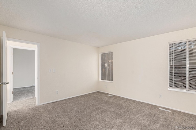 carpeted empty room with a textured ceiling