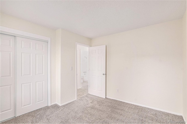 unfurnished bedroom with a closet, light colored carpet, and a textured ceiling