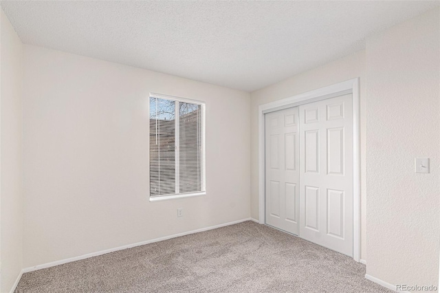 unfurnished bedroom featuring a textured ceiling, light carpet, and a closet