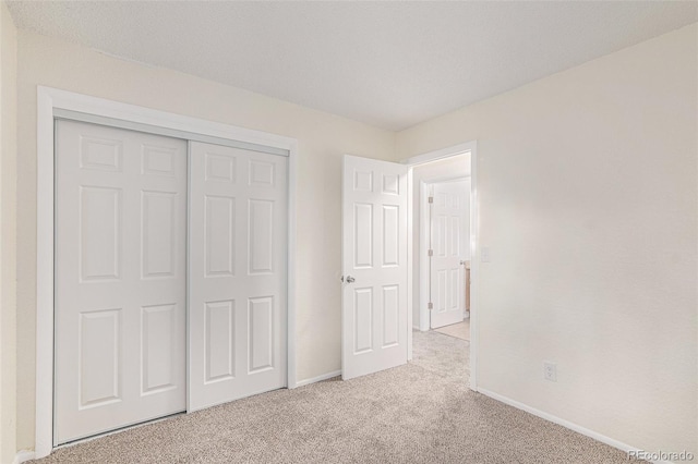 unfurnished bedroom featuring light carpet and a closet