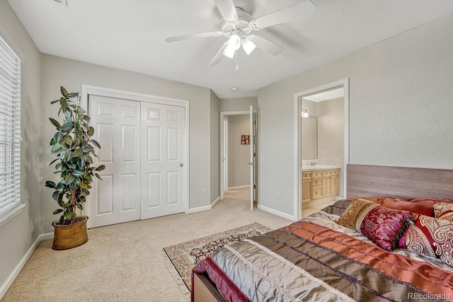 bedroom featuring connected bathroom, light colored carpet, a closet, and ceiling fan