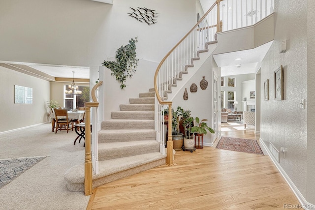 foyer with a towering ceiling, an inviting chandelier, and hardwood / wood-style floors