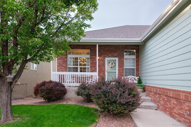 6245 Fencerail Hts, Colorado Springs, CO 80919 - property entrance with a porch, brick siding, and roof with shingles