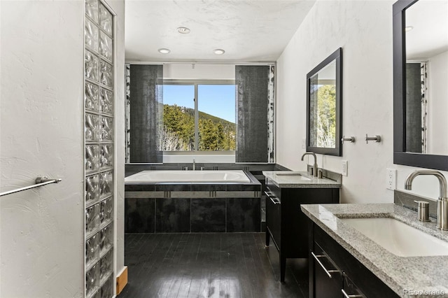 10508 Christopher Dr, Conifer, CO 80433 - full bathroom with two vanities, a bath, and hardwood / wood-style flooring