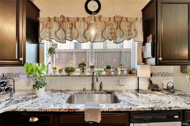 19447 E Bellisario Creek Dr, Parker, CO 80134 - kitchen featuring a sink, stainless steel dishwasher, dark brown cabinetry, backsplash, and light stone counters