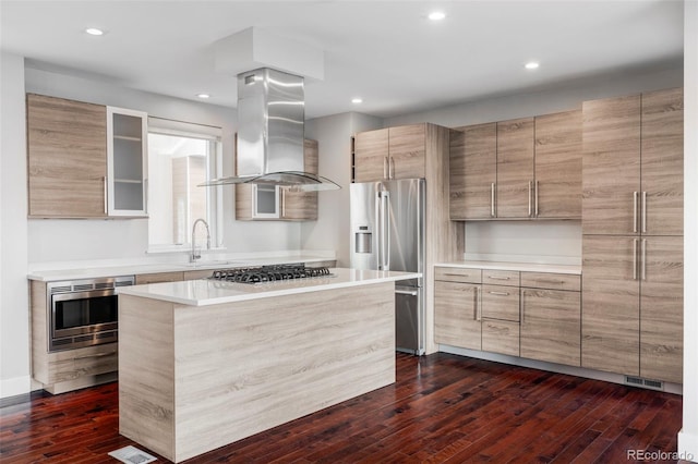 kitchen featuring dark wood-type flooring, island exhaust hood, a kitchen island, appliances with stainless steel finishes, and sink