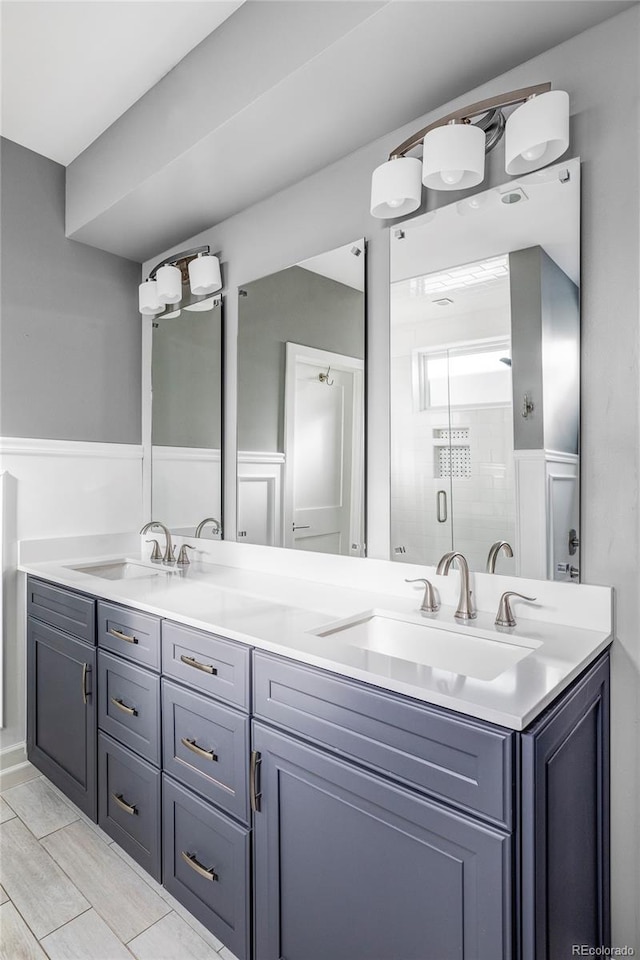 bathroom featuring a shower with shower door and vanity