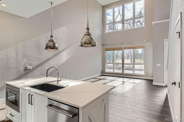 kitchen featuring light stone countertops, appliances with stainless steel finishes, white cabinetry, a healthy amount of sunlight, and sink