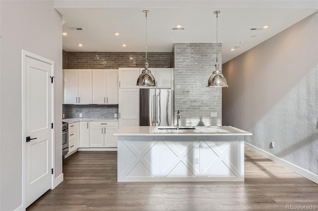 kitchen featuring appliances with stainless steel finishes, white cabinetry, tasteful backsplash, sink, and hanging light fixtures