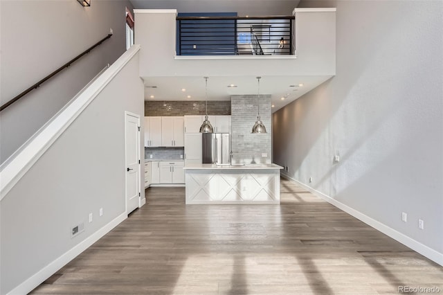 unfurnished living room with a high ceiling, wood-type flooring, and sink