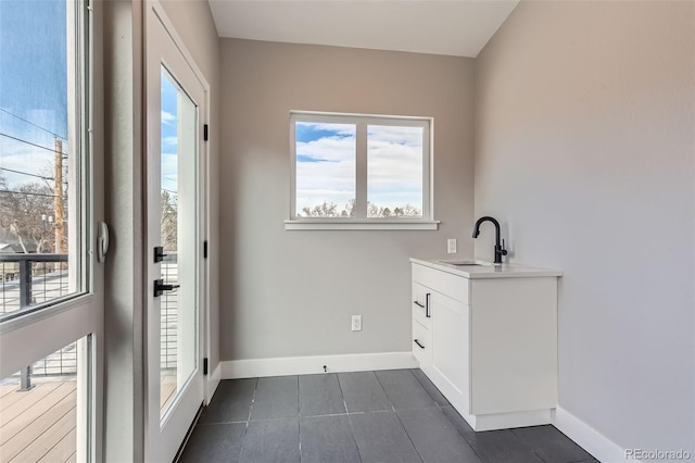 doorway to outside with sink and dark tile patterned flooring