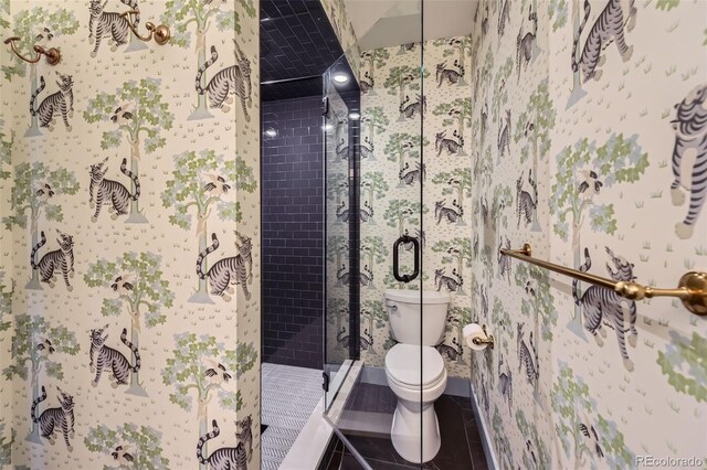 bathroom featuring toilet, a shower with shower door, and tile patterned floors