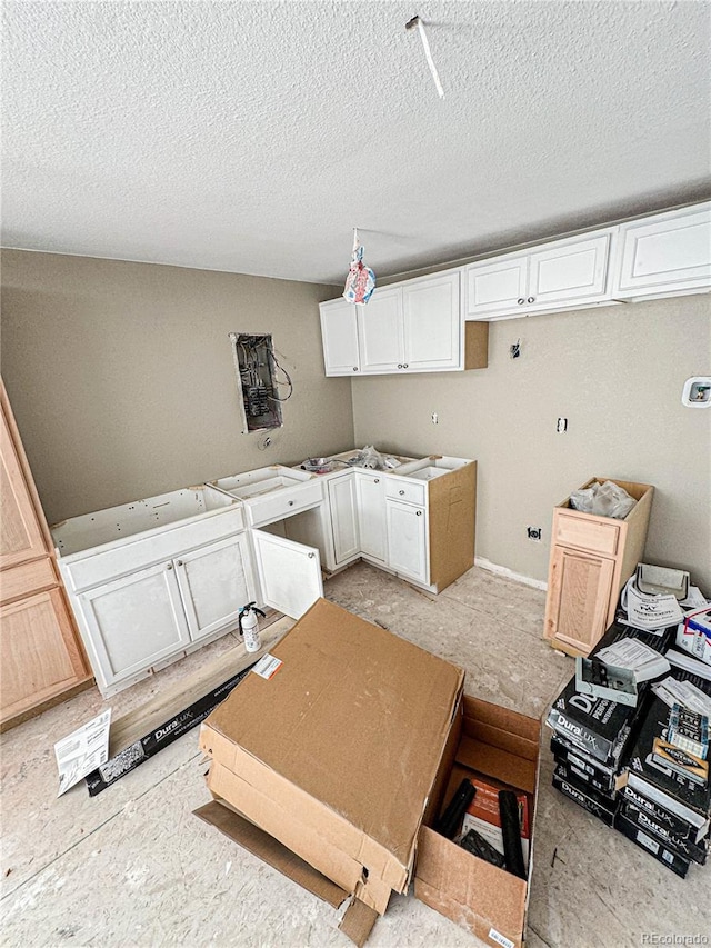 kitchen with white cabinets, a textured ceiling, and light brown cabinetry