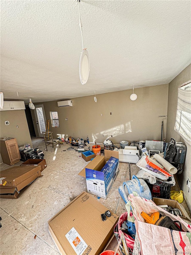 miscellaneous room featuring an AC wall unit and a textured ceiling